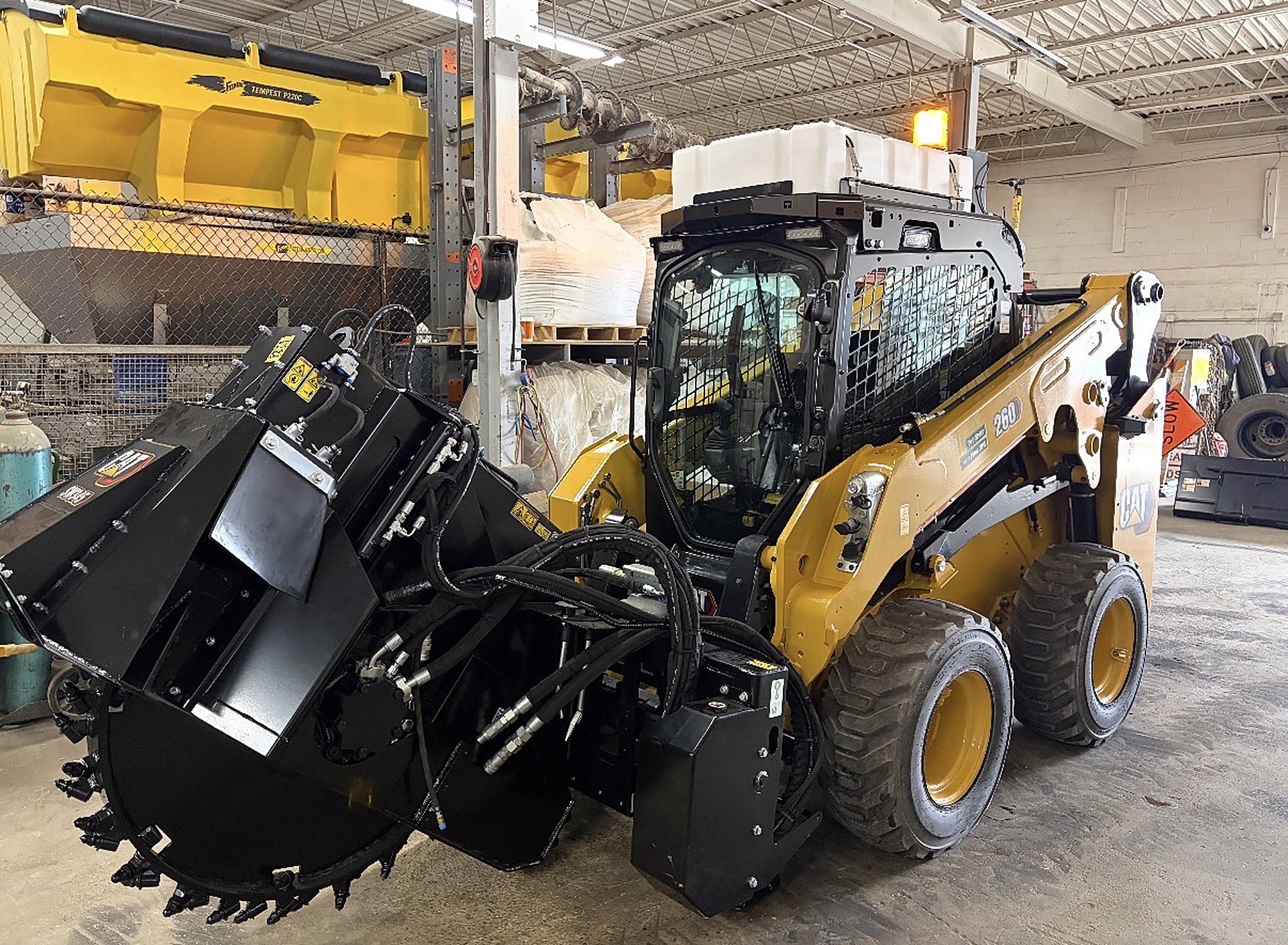 Mass Pipeline Services skid steer loader with a wheel saw attachment stored in the equipment shop